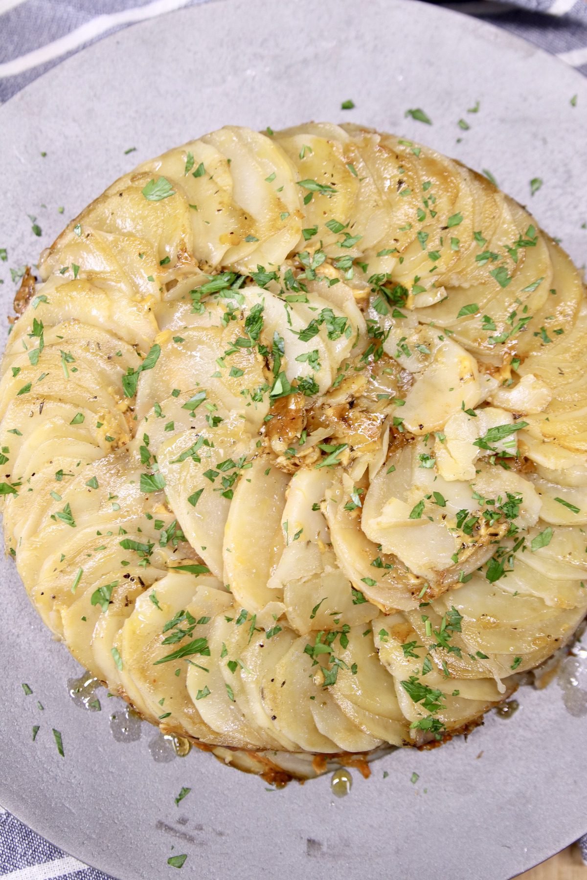 gray platter with round potatoes au gratin, topped with herbs