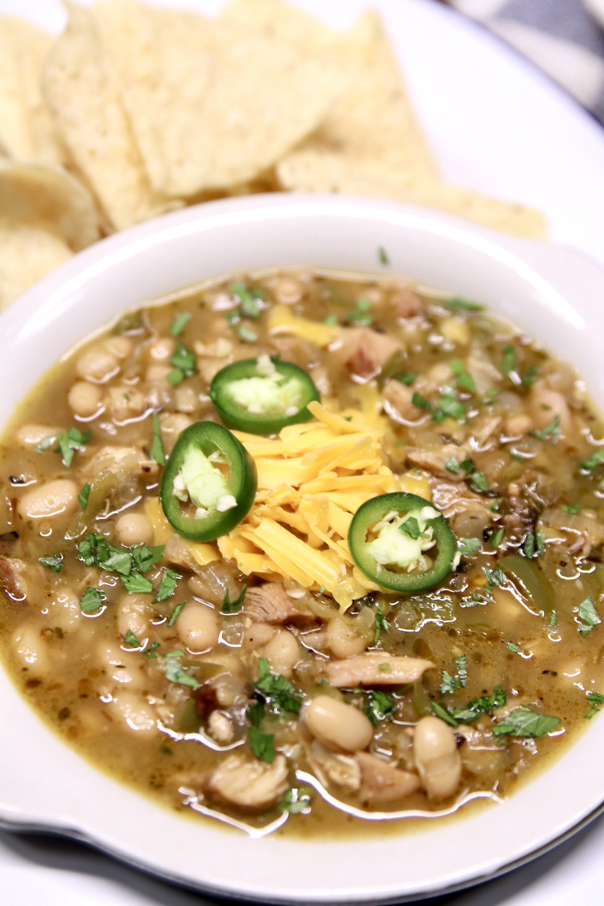 bowl of white bean chili with smoked chicken, tray with tortilla chips