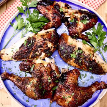 grilled chicken pieces on a blue plate with parsley garnish