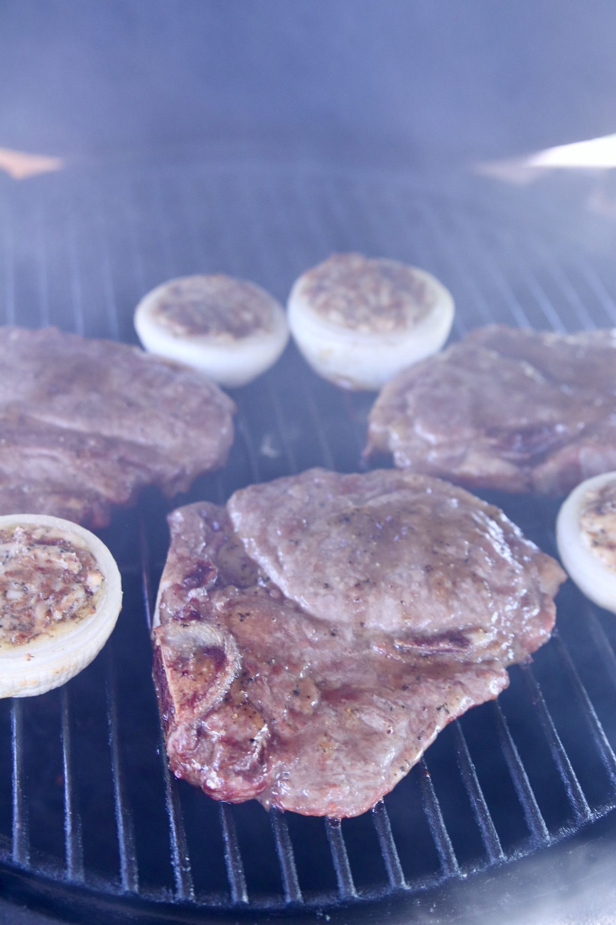 grilled steaks with stuffed onions on a grill