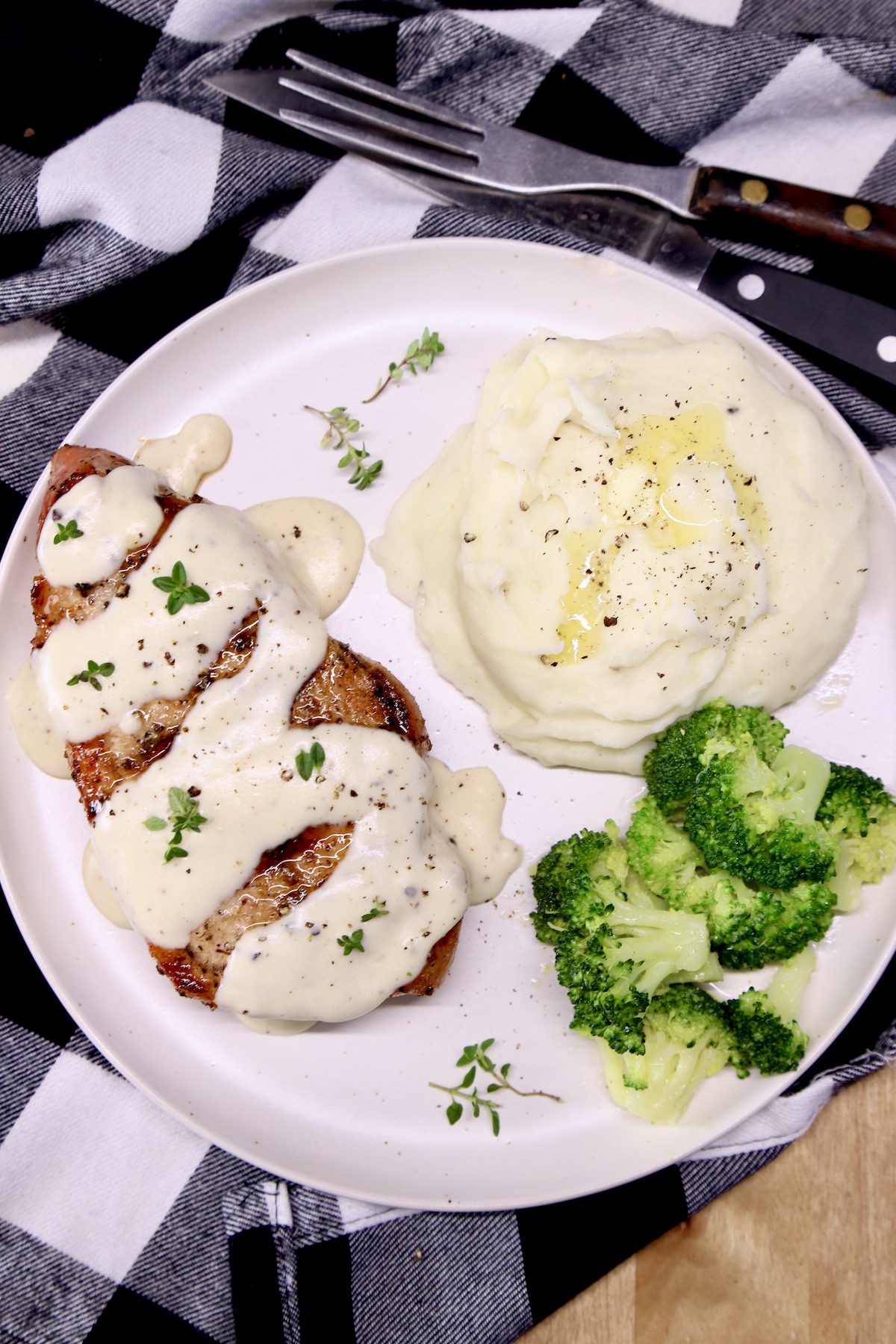 grilled pork chop with sour cream sauce, mashed potatoes, broccoli on a plate