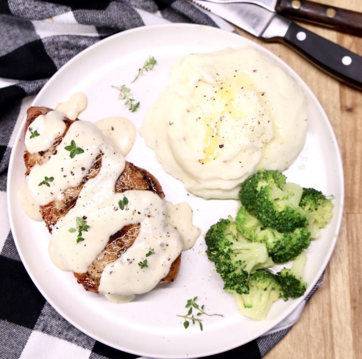 Sour cream pork chop on a plate with mashed potatoes and broccoli