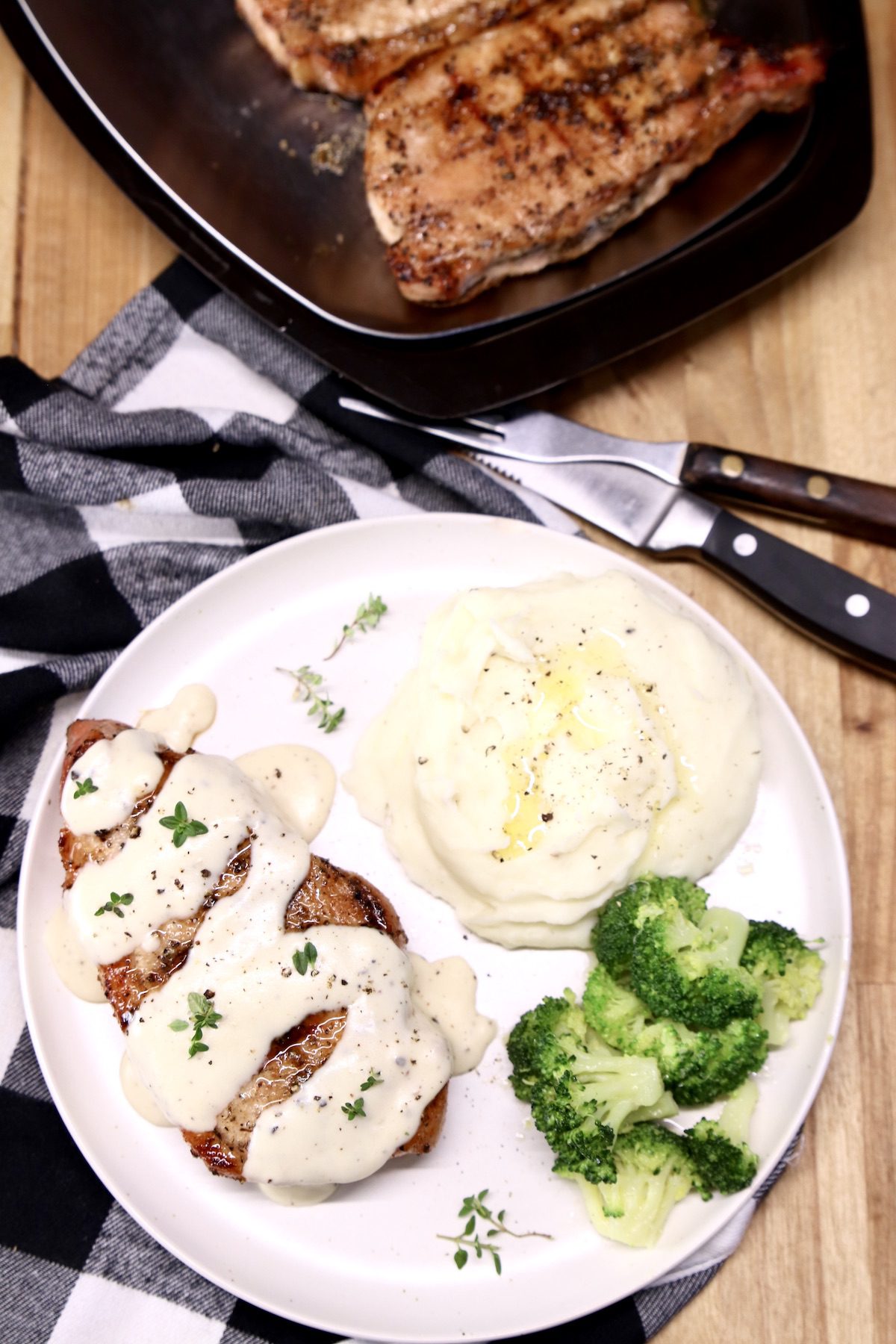 grilled pork chop on a plate with sour cream gravy, mashed potatoes and broccoli