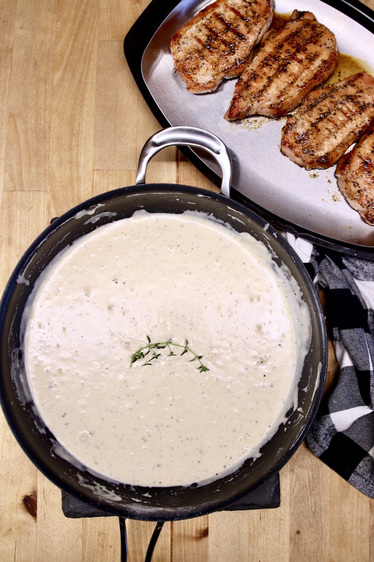 sour cream sauce in a skillet with platter of pork chops