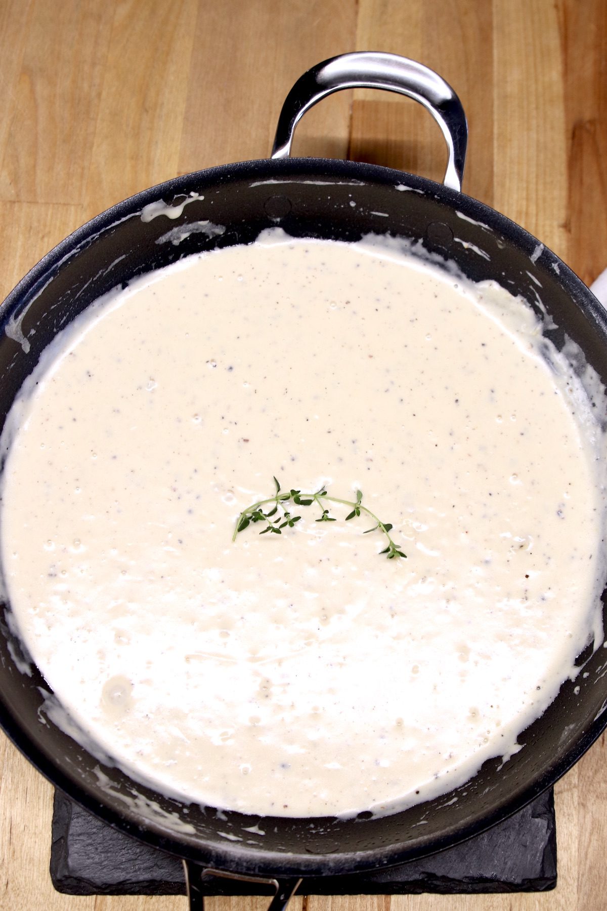skillet of sour cream sauce with thyme garnish