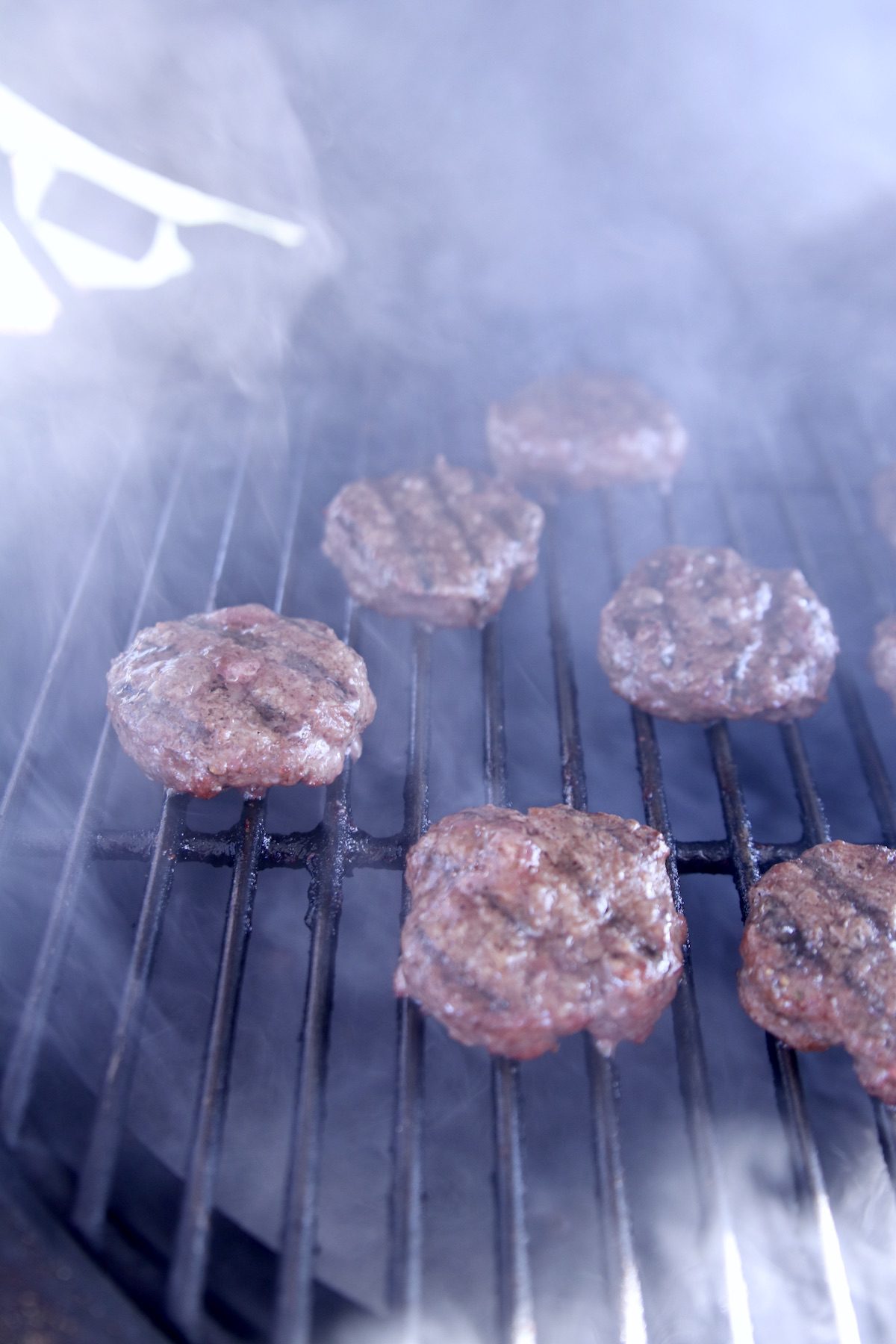 burgers on a grill with smoke