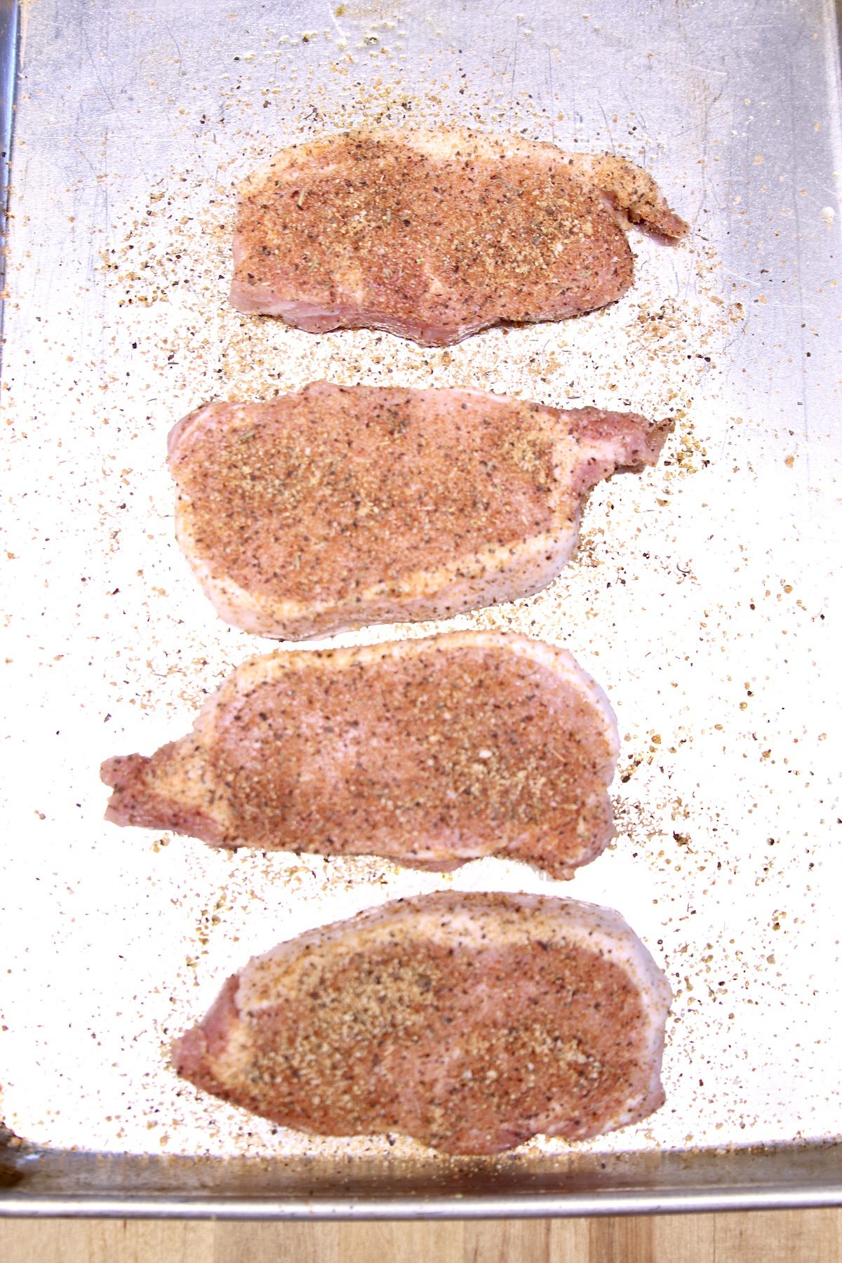 sheet pan with 4 seasoned pork chops - raw