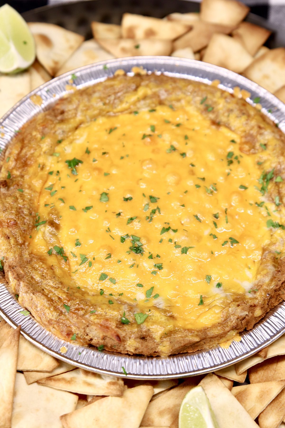 Cheesy Bean Dip in a foil pie plate with tortilla chips