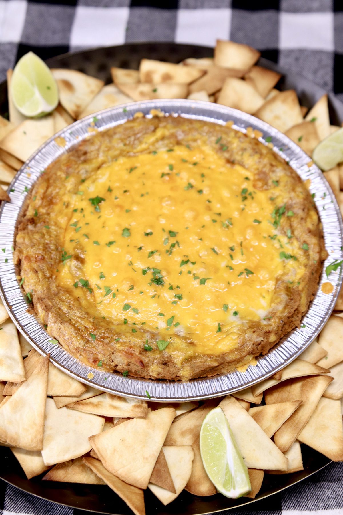 platter of tortilla chips with cheesy bean dip in center