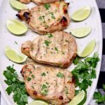 platter of 4 pork chops with sliced limes and cilantro - text overlay