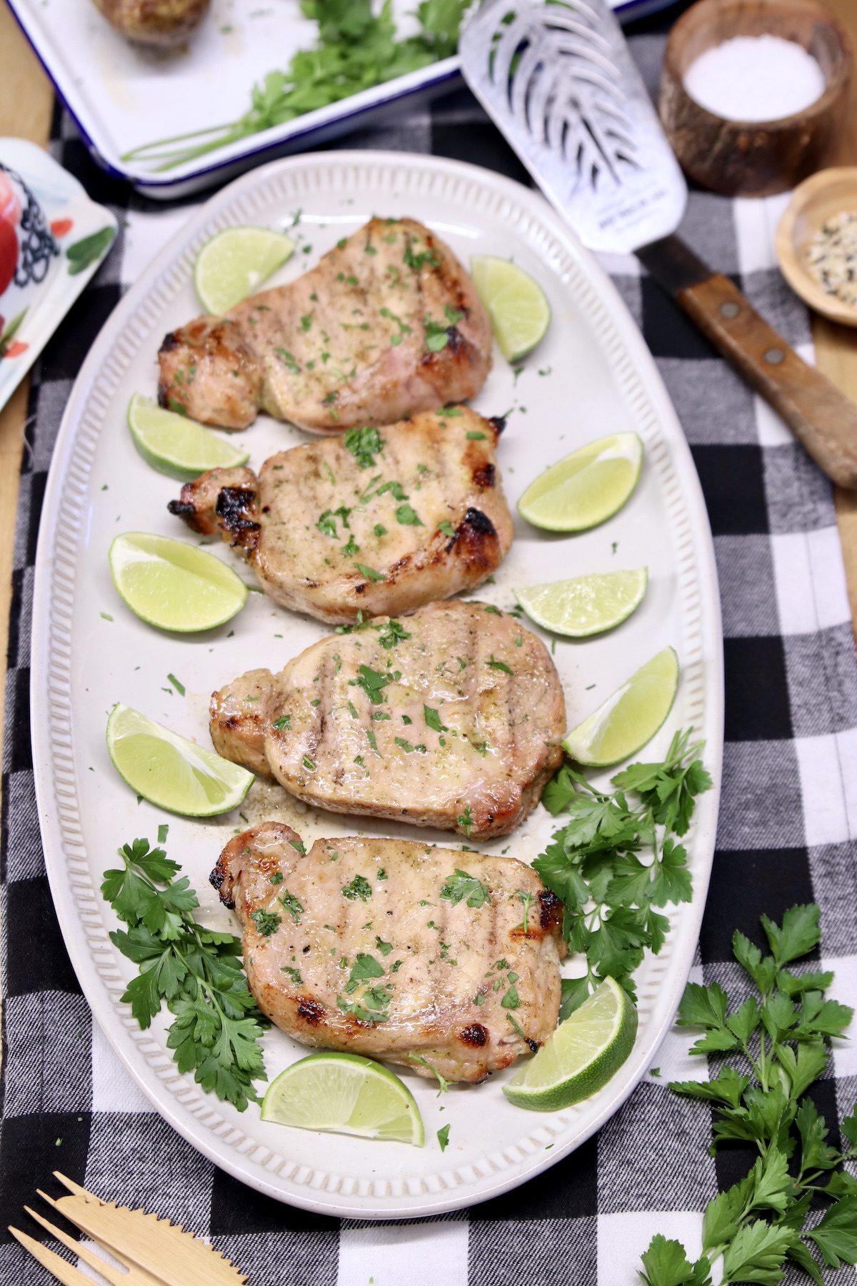 grilled pork chops on a platter with limes and cilantro