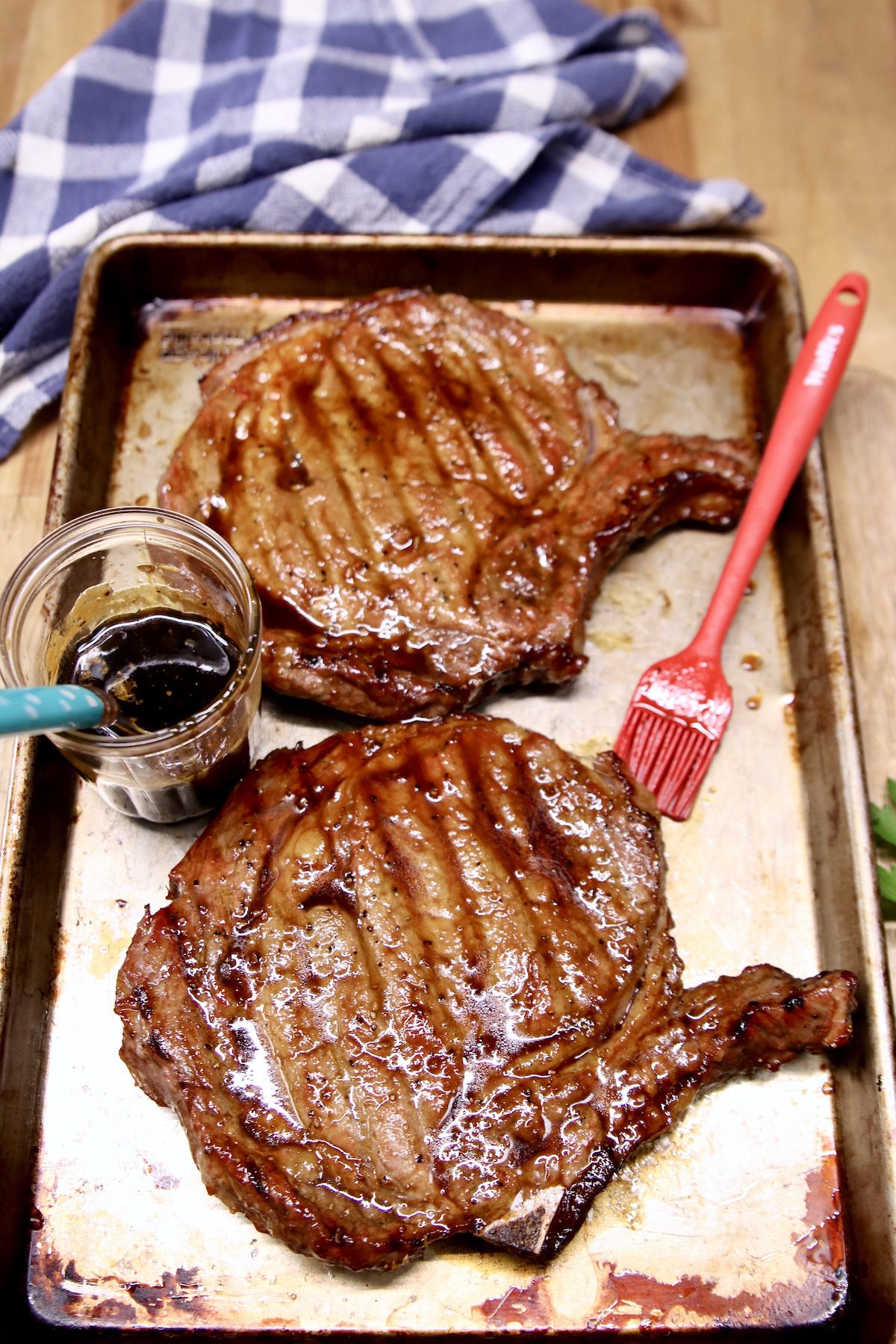 grilled steaks on a baking sheet with jar of whiskey butter and brush