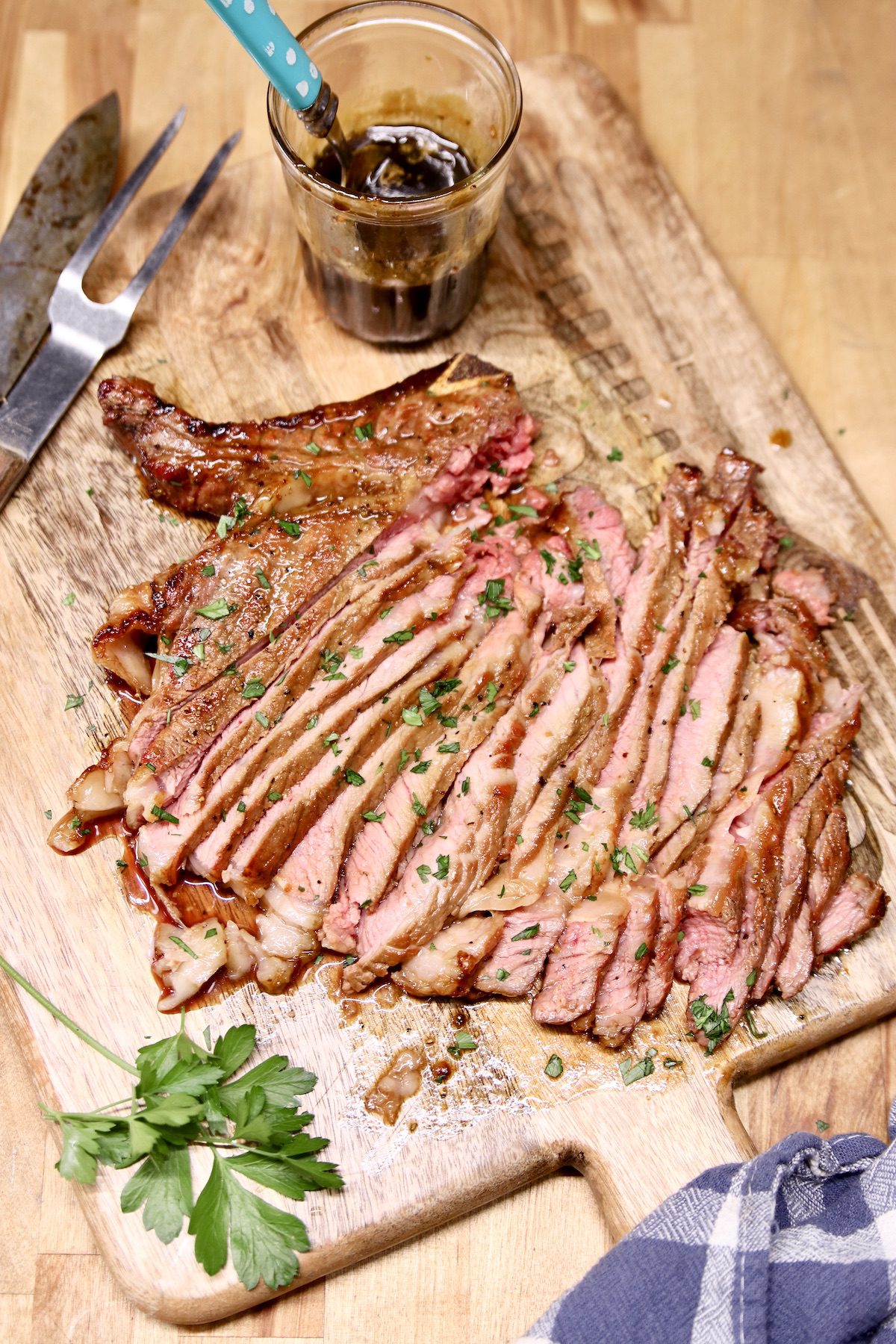 sliced steak with whiskey butter on a cutting board