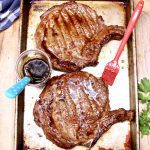 2 grilled ribeye steaks on a sheet pan with jar of whiskey butter