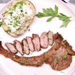 Grilled Venison Chop on a plate, with sliced steak and baked potato