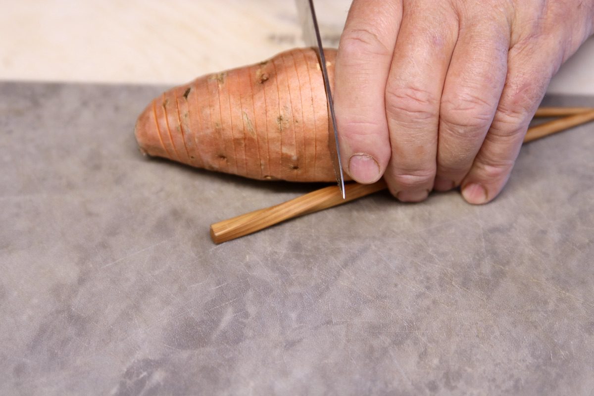 cutting a sweet potato into hassleback slices