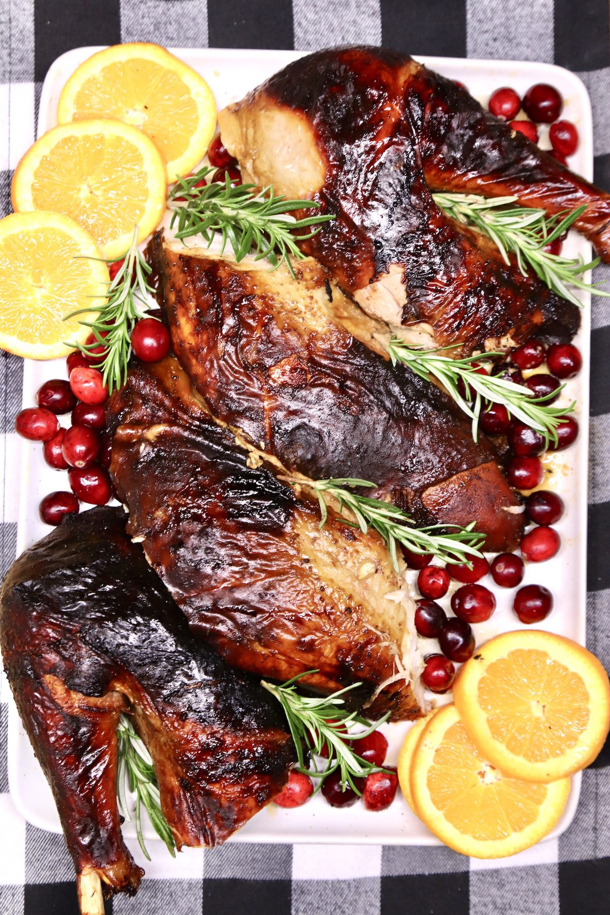 grilled turkey, cut up on a platter with oranges and cranberries