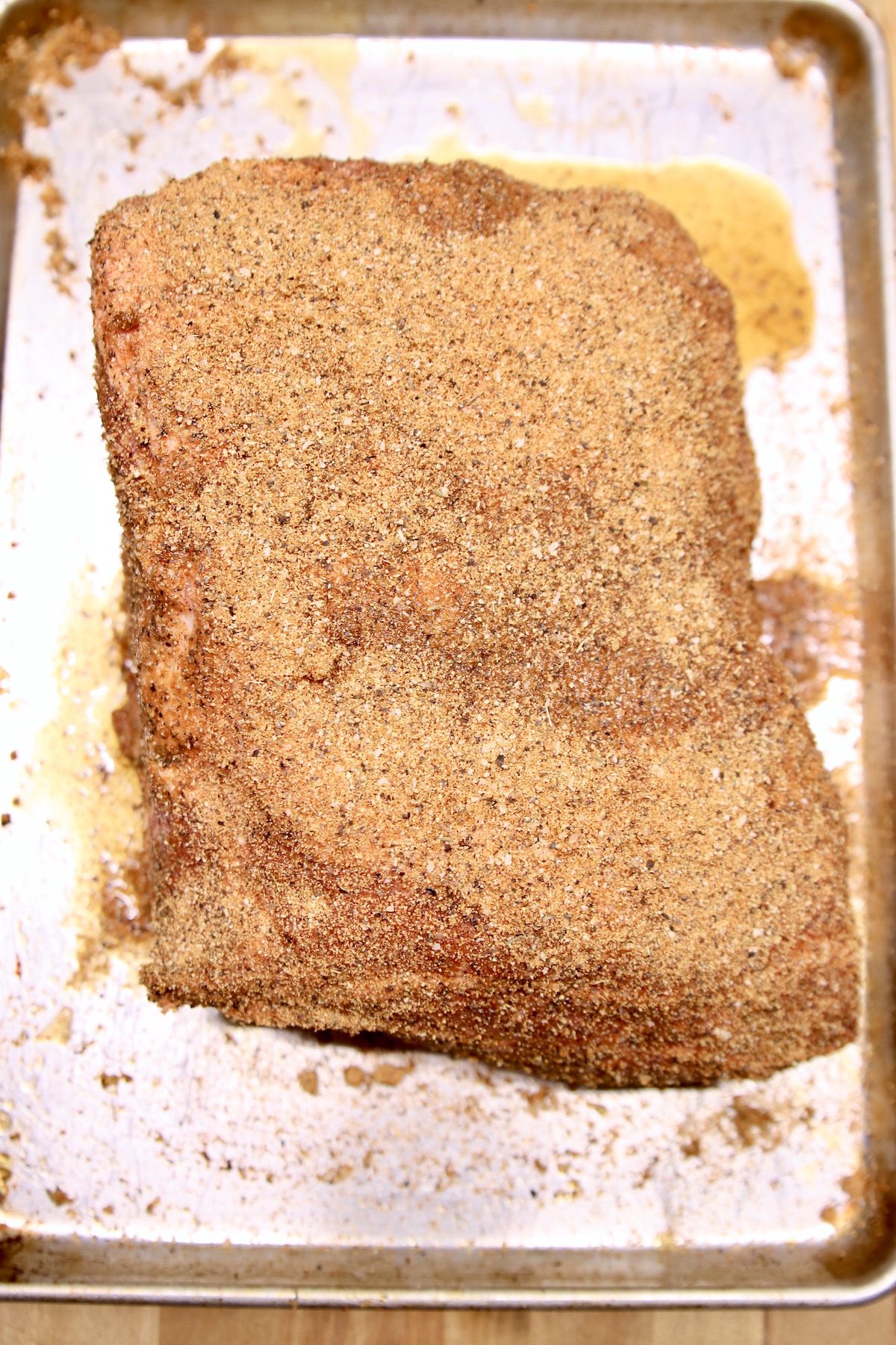 pork butt with dry rub on a sheet pan