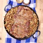 platter with grilled steaks & fries on a blue plaid table runner