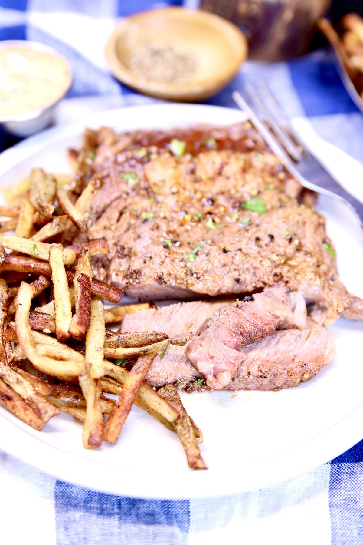 ribeye steak partially sliced on a plate with fries