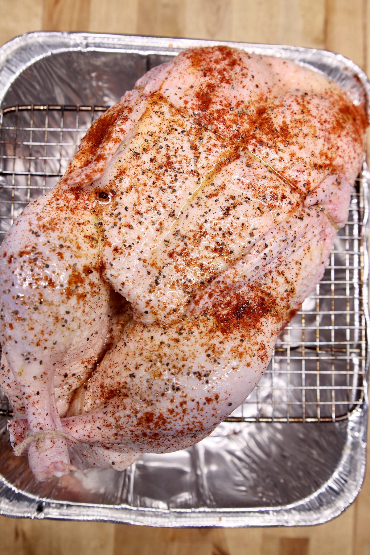 seasoned whole chicken on a wire rack over a roasting pan