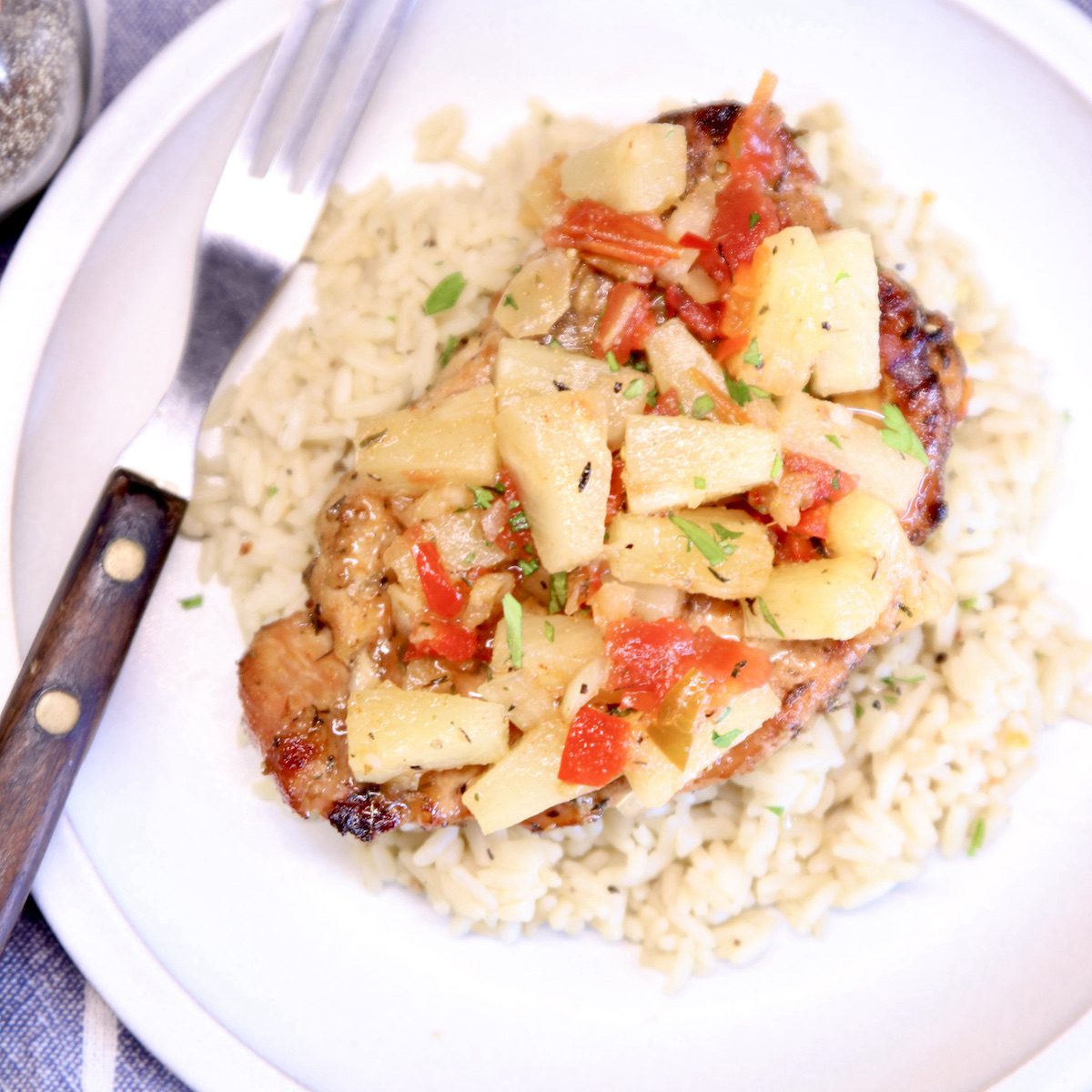 plate of rice, pork chop topped with pineapple salsa