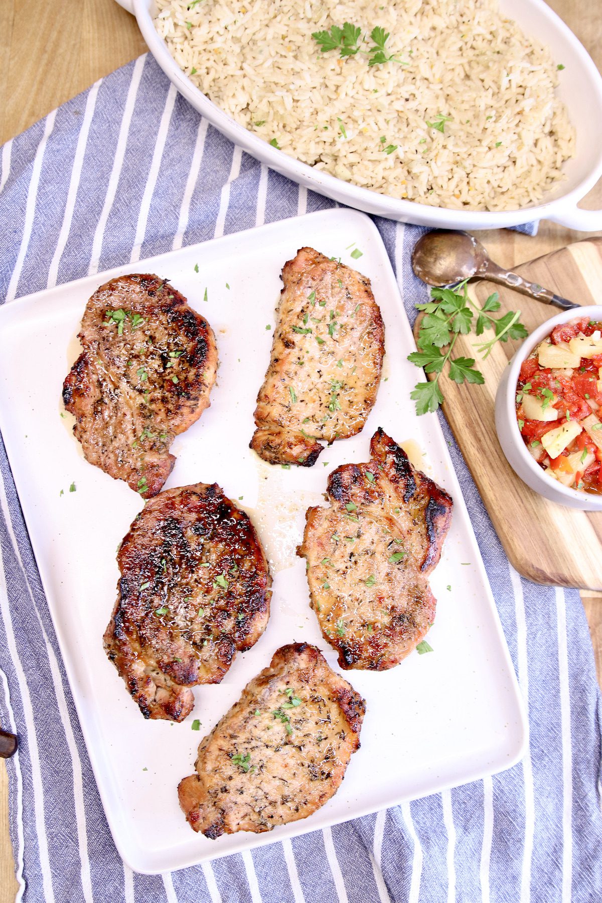 grilled pork chops on a platter with rice pilaf and salsa