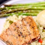 maple glazed salmon plated with rice, asparagus and a dinner roll.