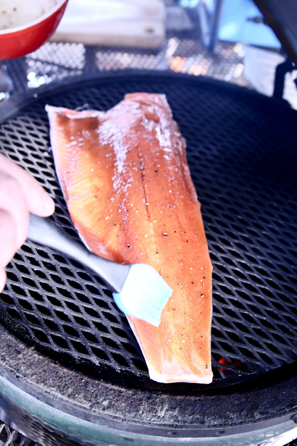 brushing glaze over salmon filet on a grill.