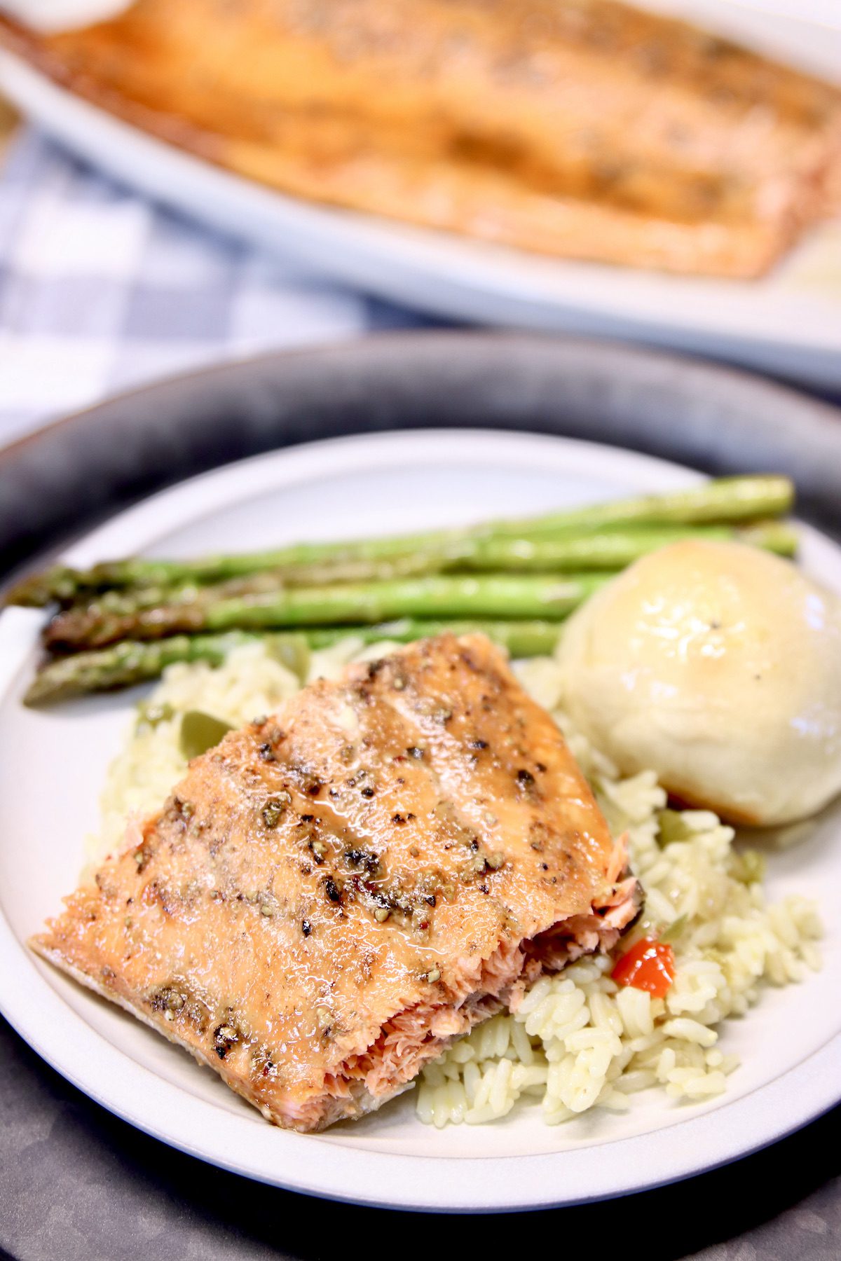 grilled salmon plated with rice, roll and asparagus.