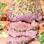 Parmesan Crusted Beef Tenderloin Roast - partially sliced on a cutting board