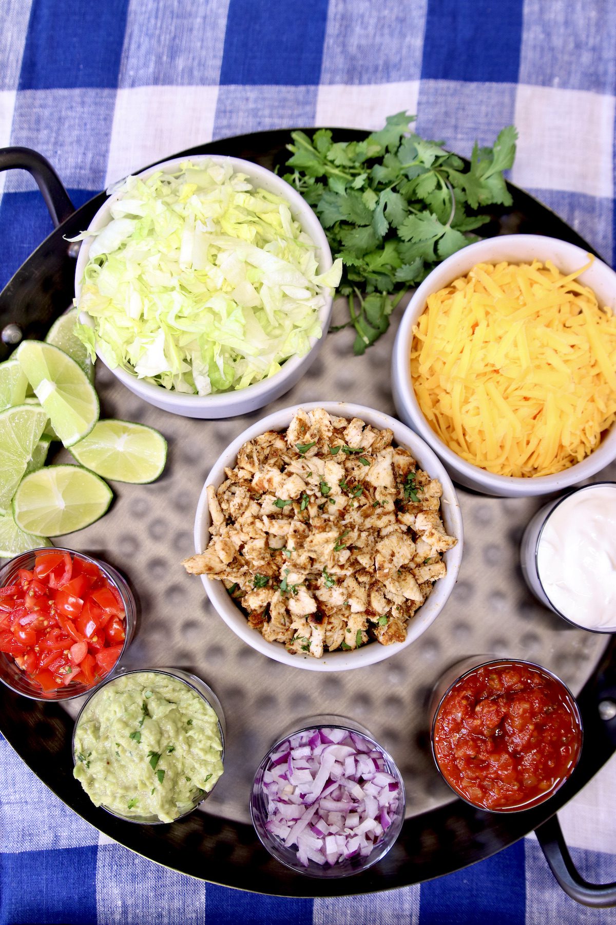 round tray with chopped chicken and toppings for tacos.