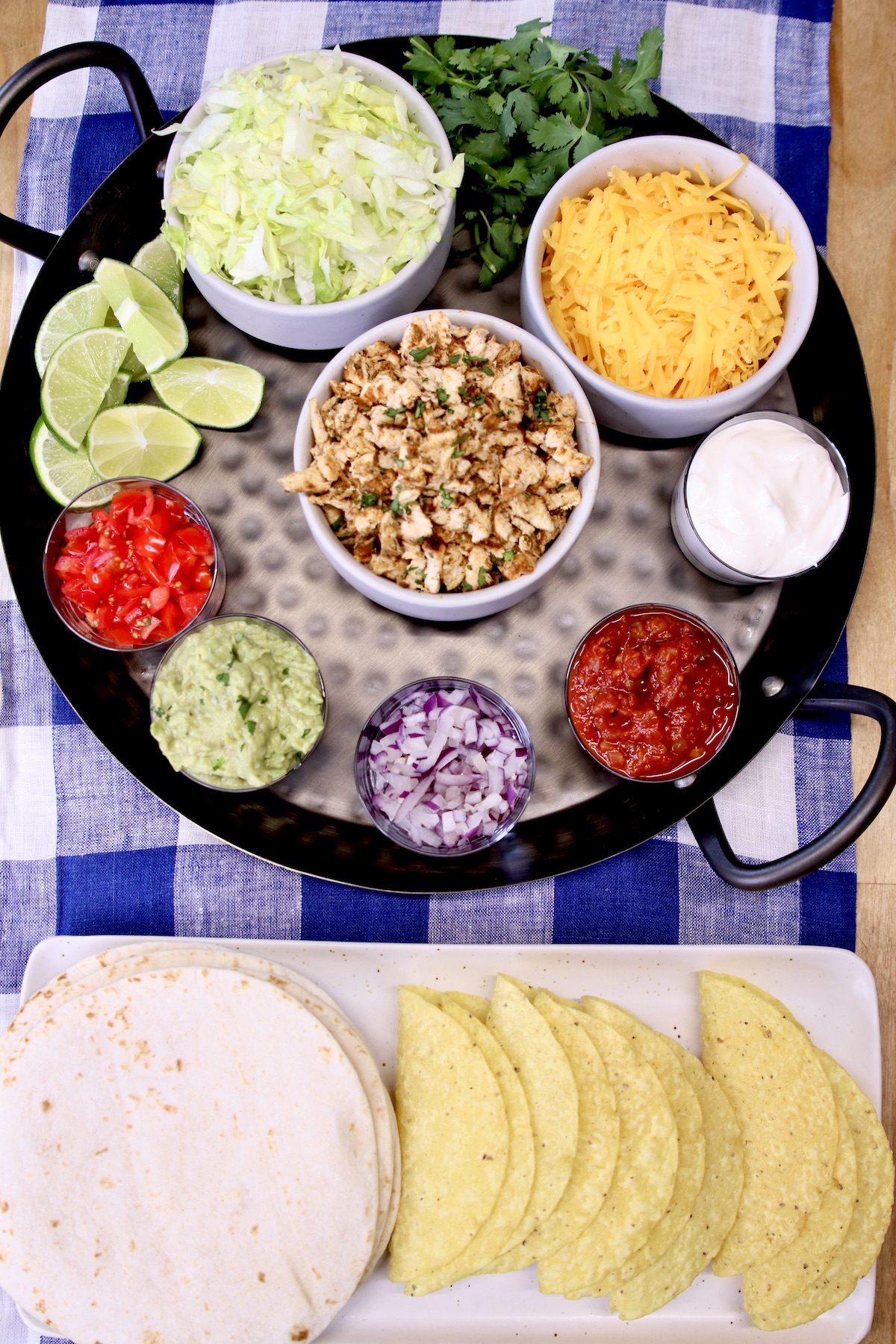 Round tray with chicken taco toppings, tray of flour tortillas and crispy taco shells.