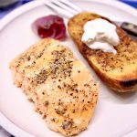 grilled salmon filet with baked potato and grilled red onion on a plate