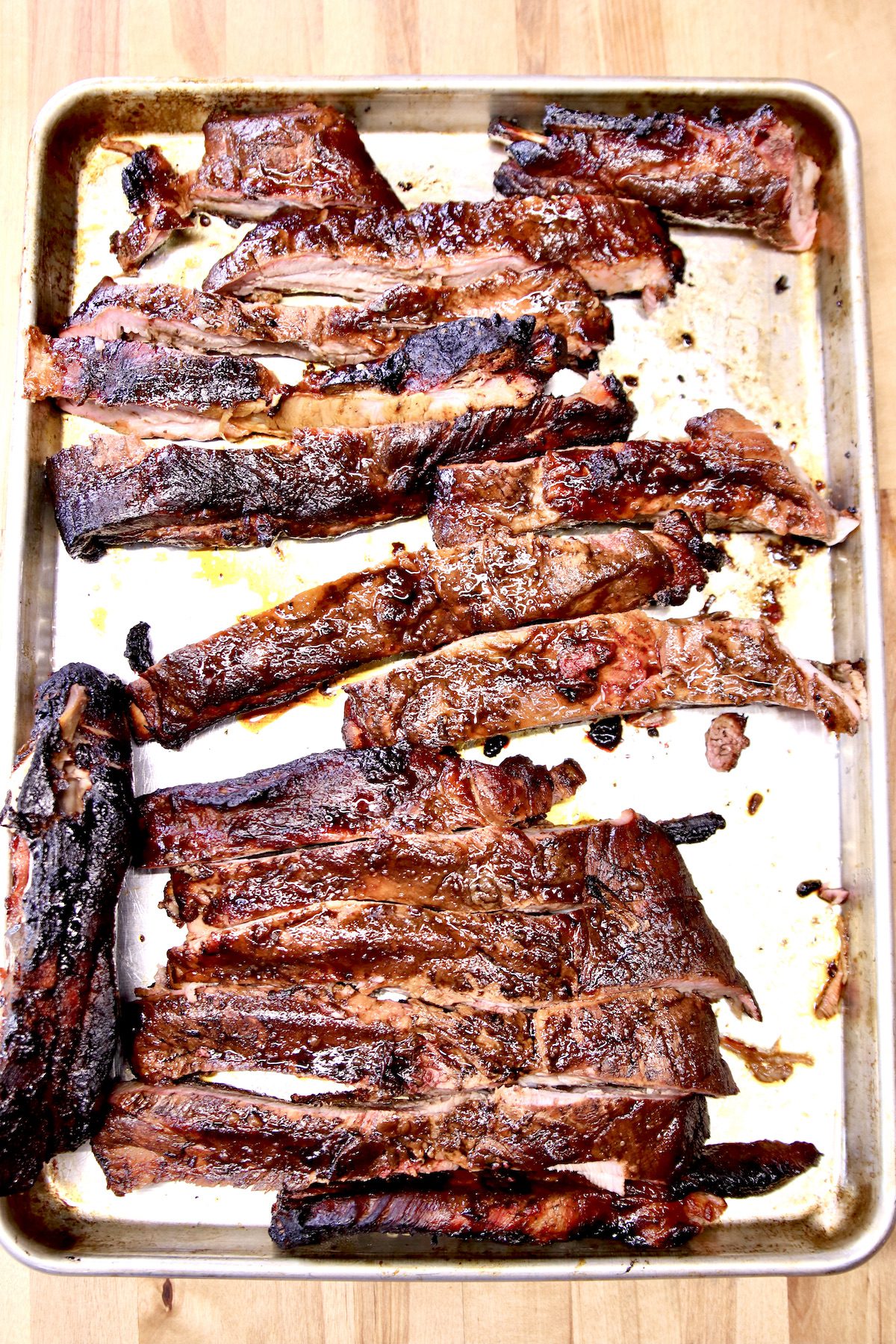 grilled spare ribs on a rimmed baking sheet.