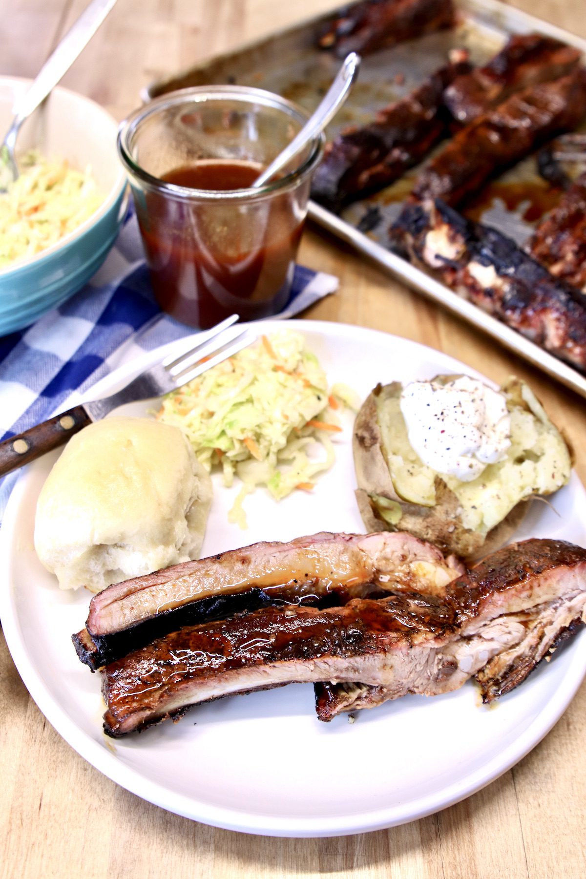 plate of spare ribs, baked potato, roll and slaw
