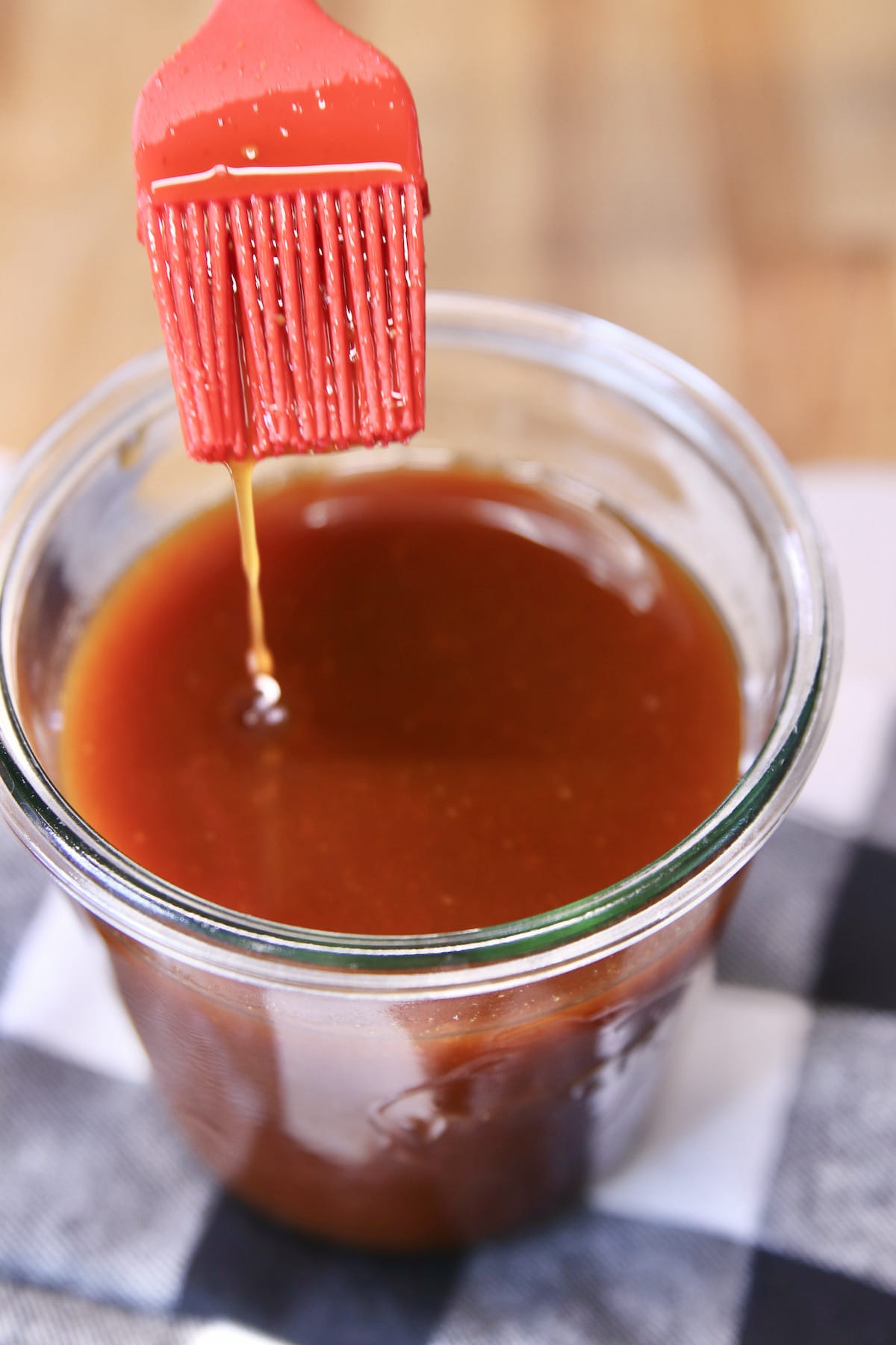 BBQ mop sauce with brush dipping into the jar of sauce.