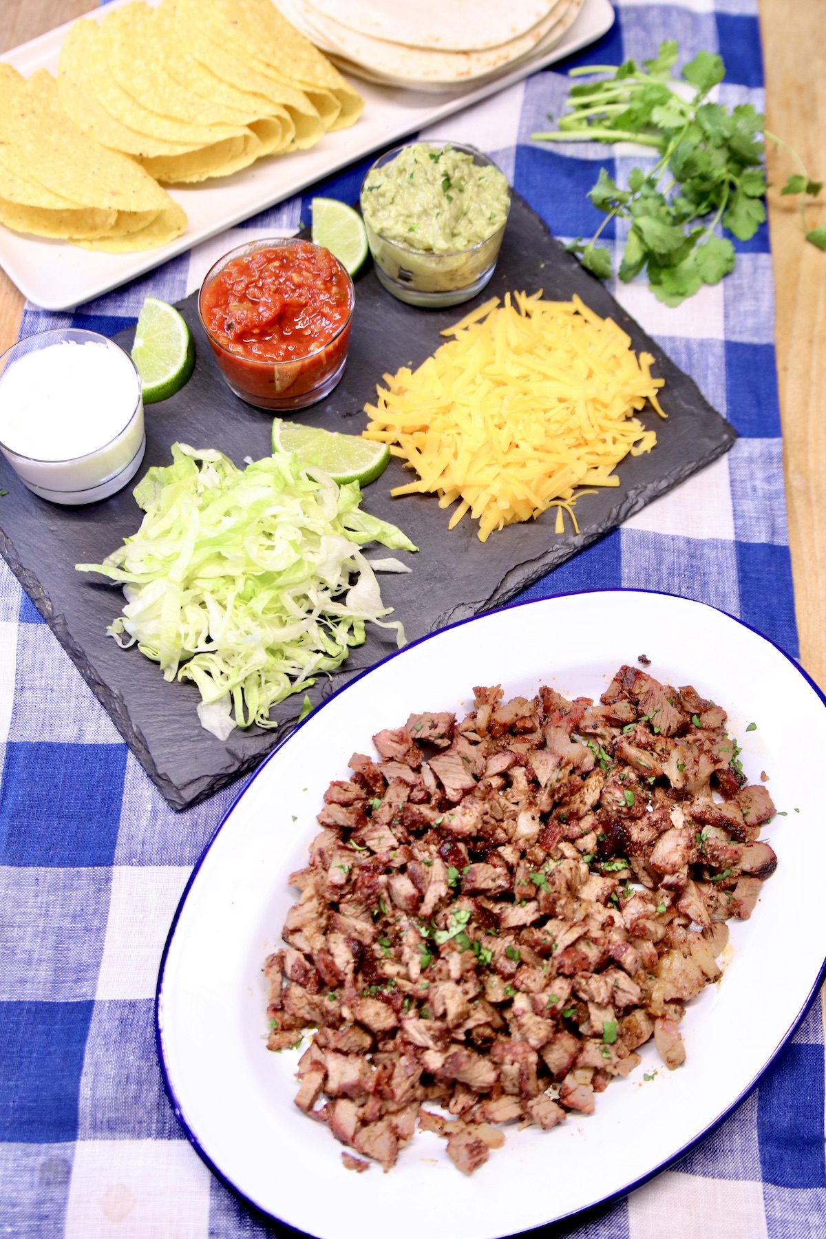 platter of chopped steak, taco toppings, taco shells.