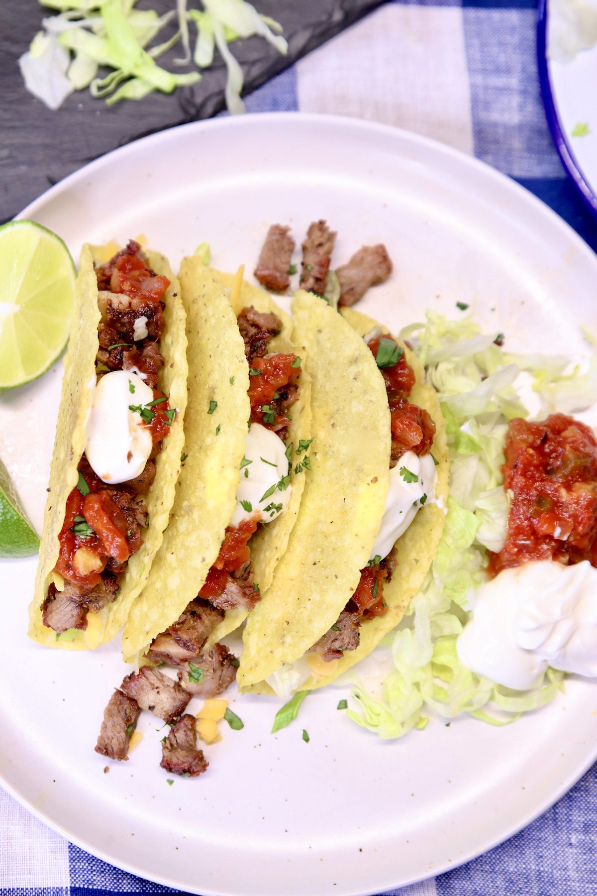 plate of 3 tacos with salsa and sour cream.