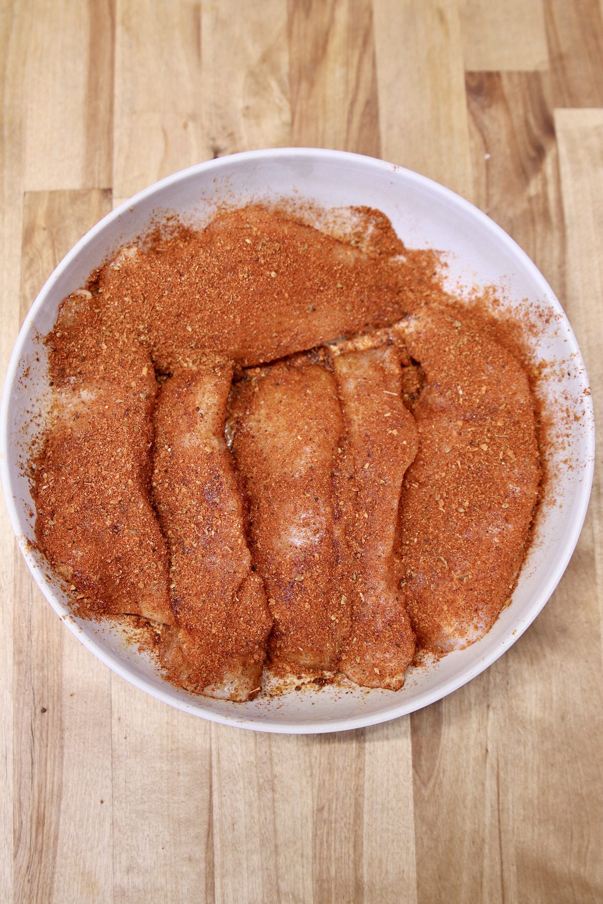 raw chicken tenders with taco seasoning in a bowl.