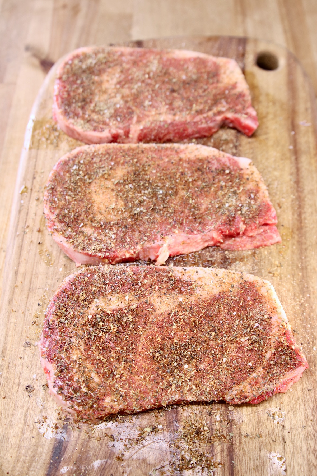 dry rub ribeye steaks on a cutting board (raw).