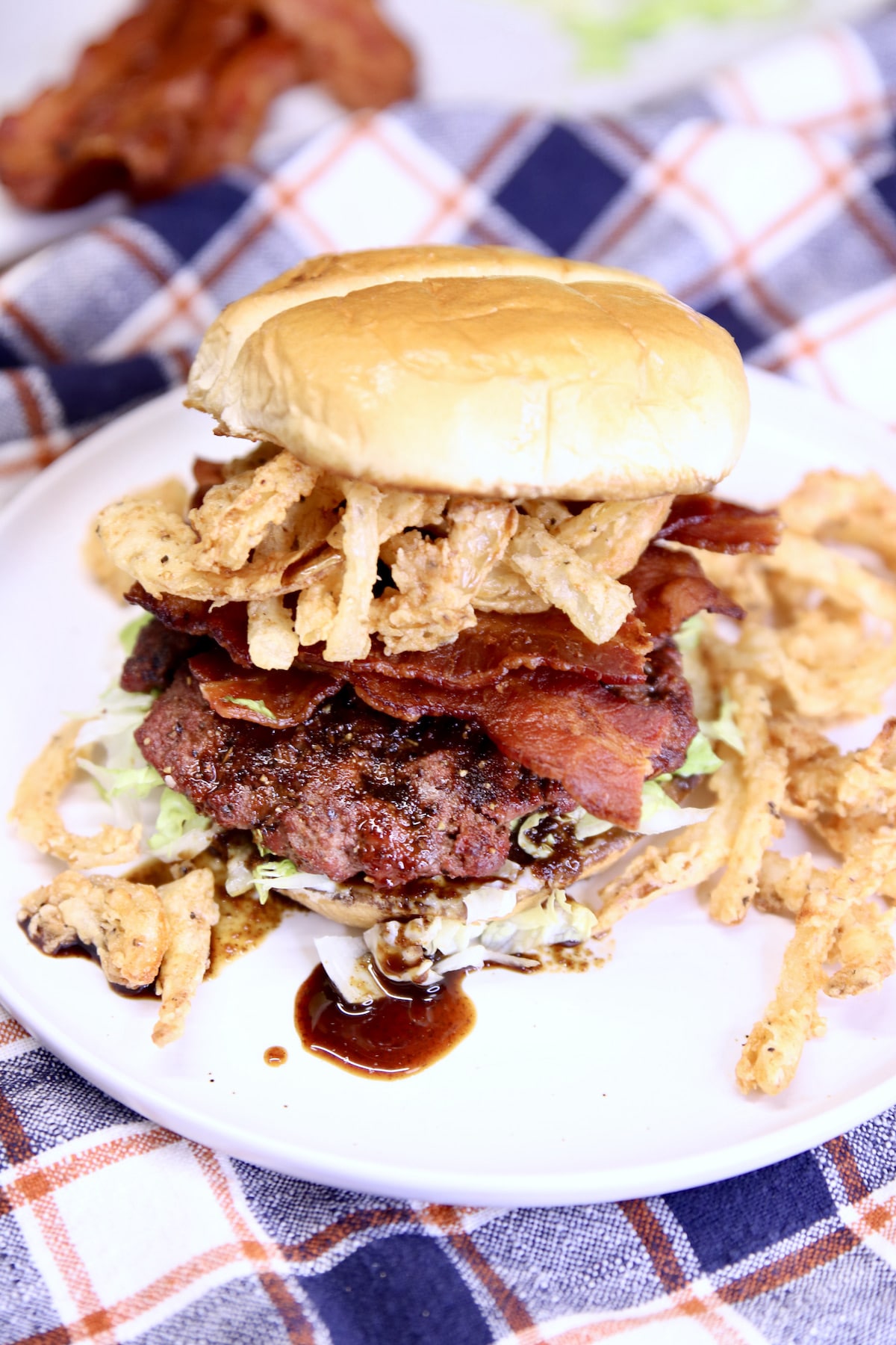 Burger with bacon and onion strings on a bun.