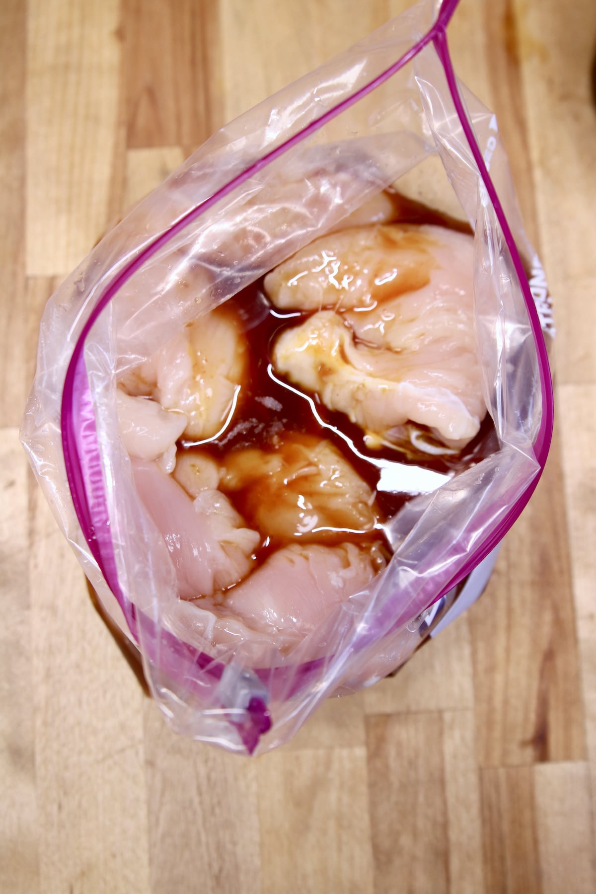 Open zip top bag with chicken tenders and marinade poured over.