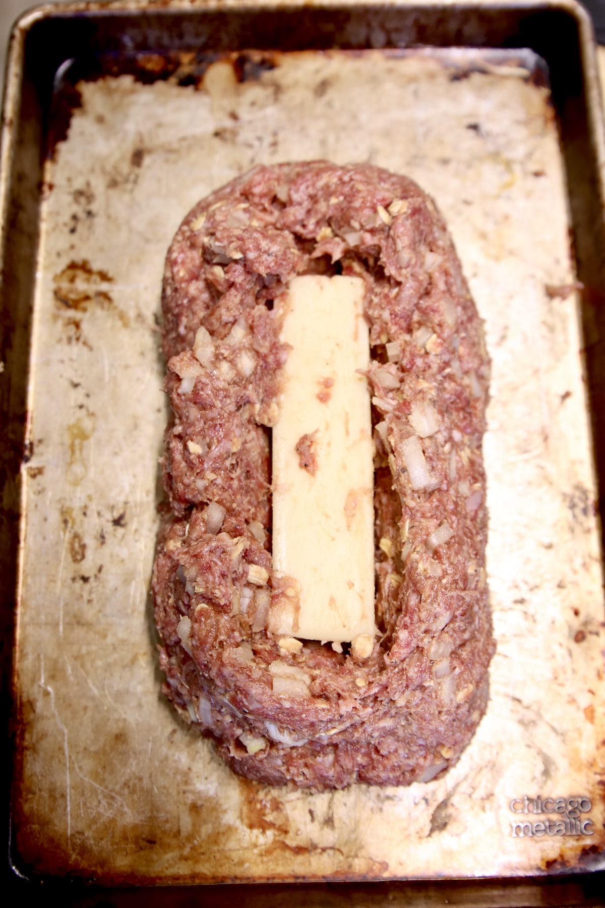 meatloaf stuffed with block of mozzarella cheese on a sheet pan before cooking.