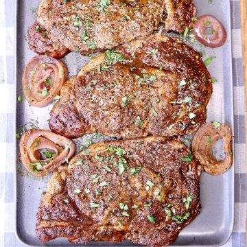 3 ribeye steaks with grilled onions.