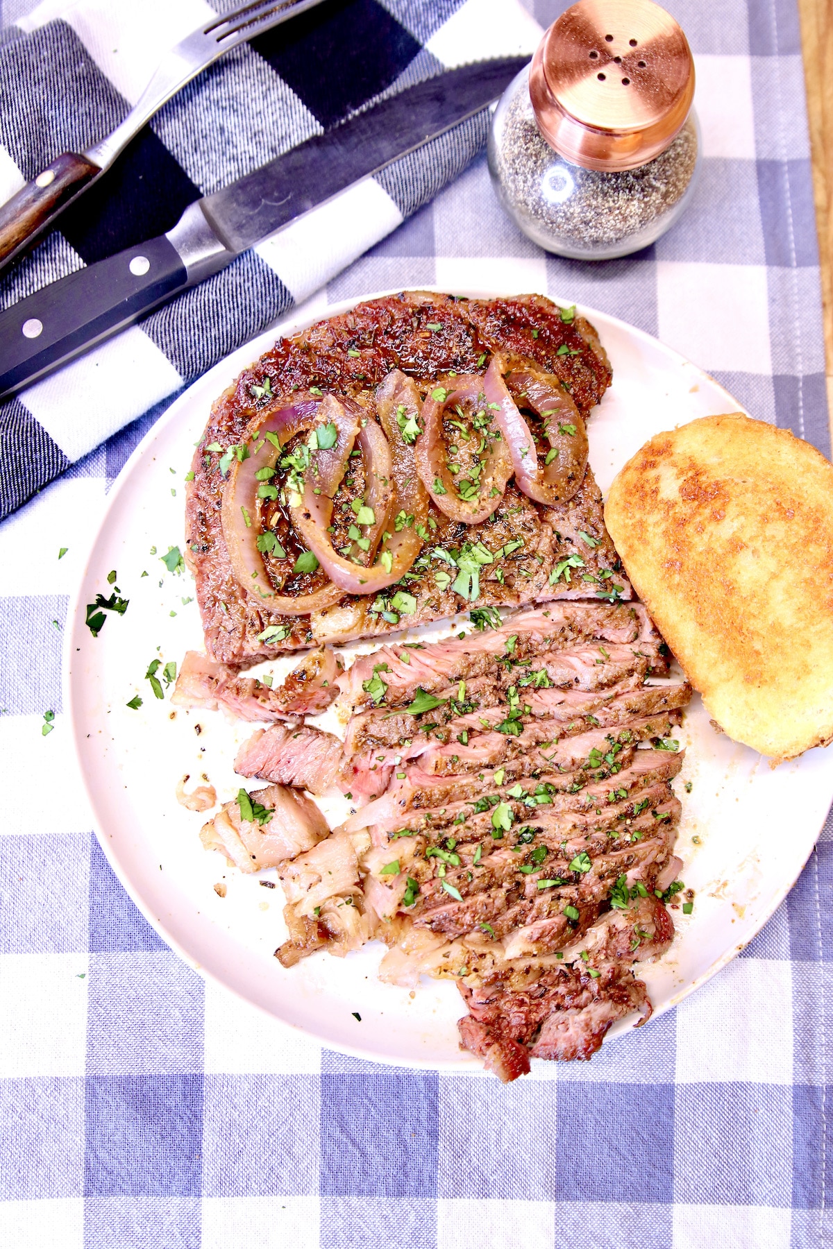 Grilled ribeye steak partially sliced with onions.