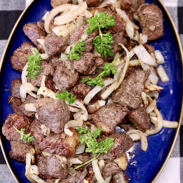 Steak bites with onions on a platter.