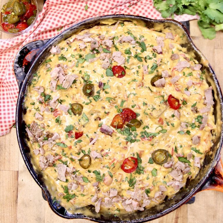 Skillet of Brisket Queso garnished with jalapenos.