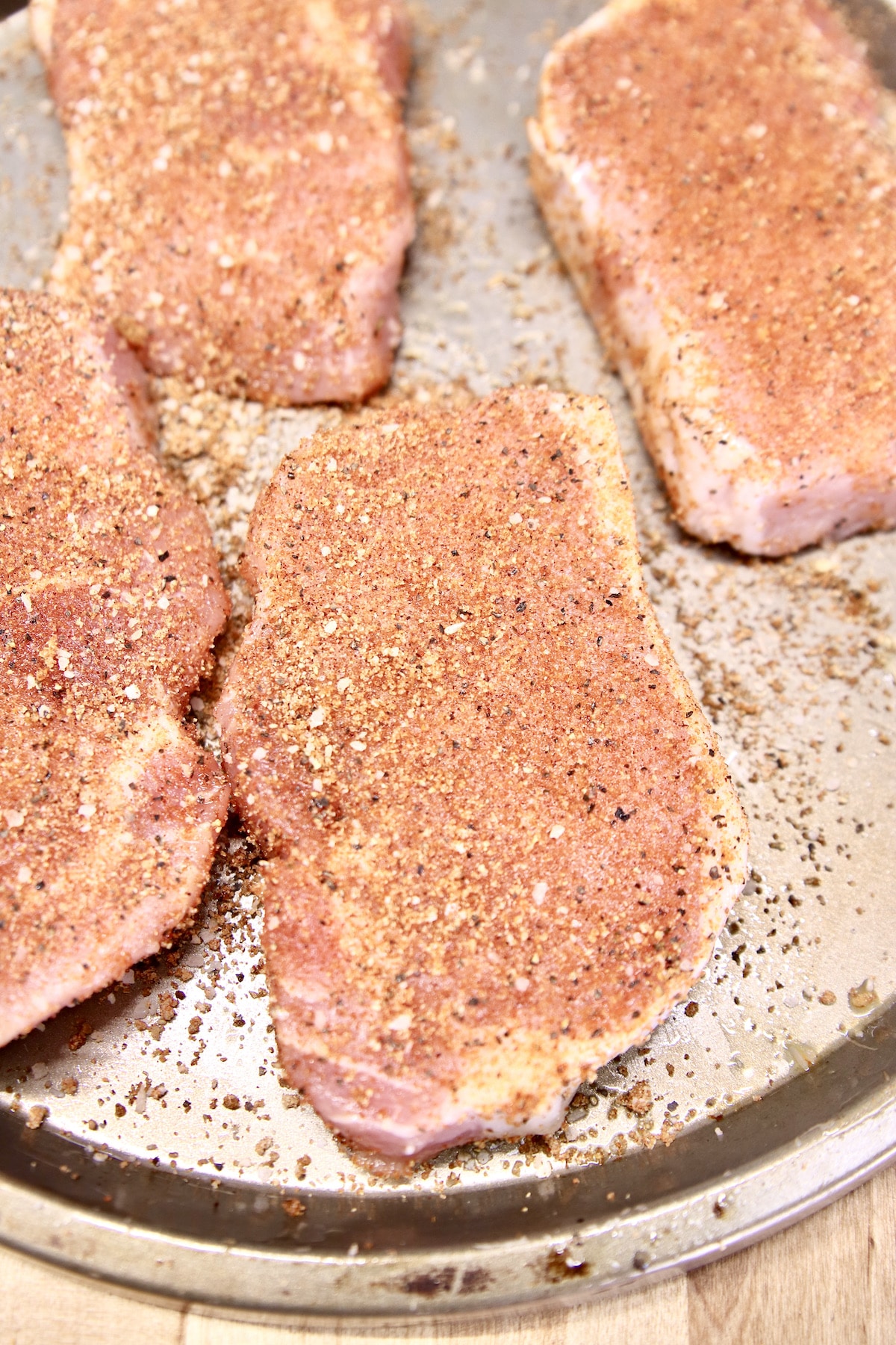 Raw pork chops with dry rub seasoning.