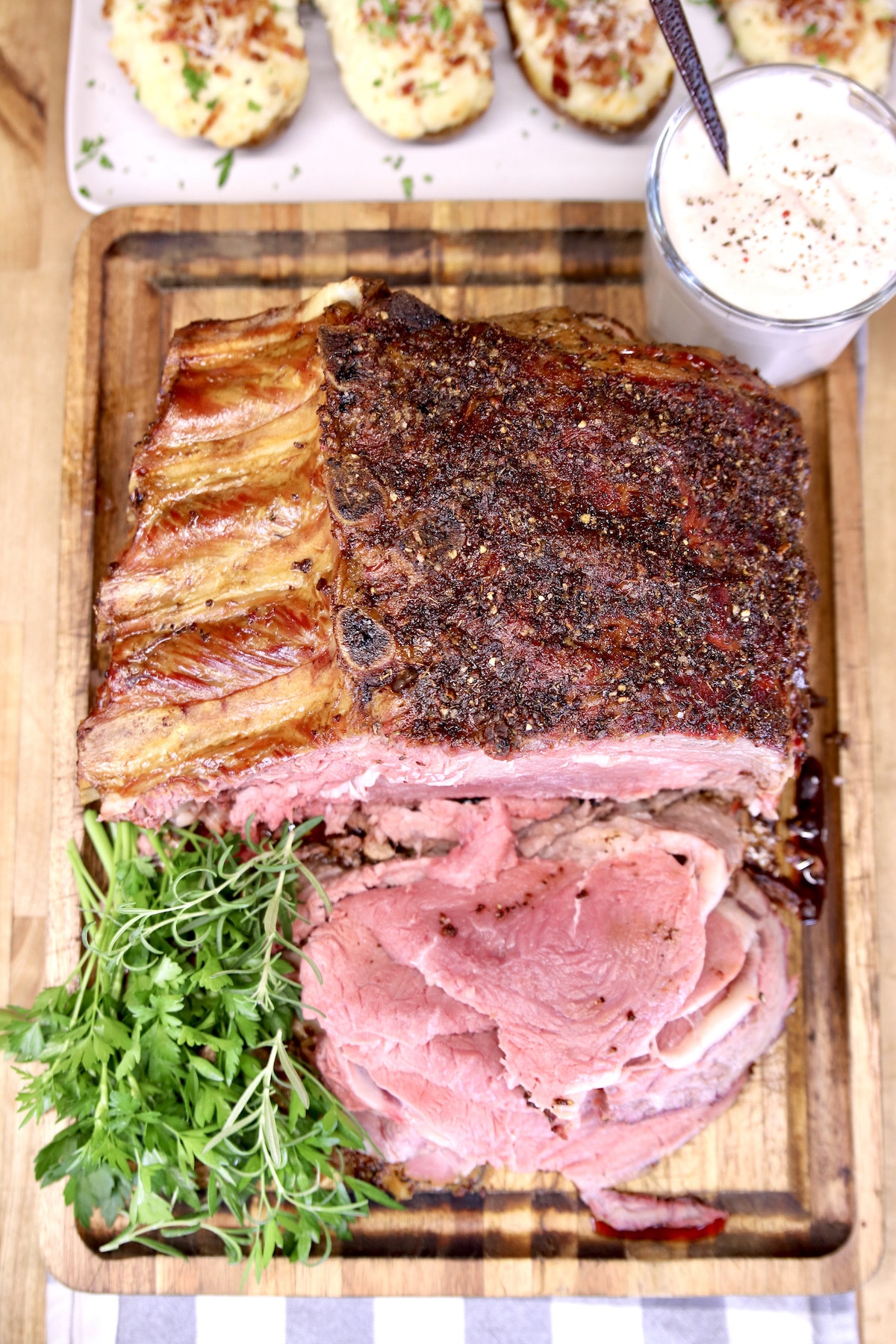 Overhead view of standing rib roast, partially sliced on cutting board.